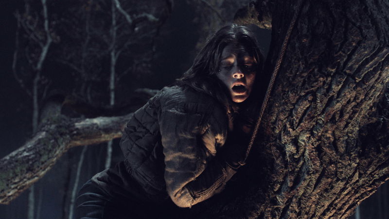 木の根へとつなぎとめられた“処刑椅子”に拘束される少女 「ヴィレッジ 声帯切村」場面写真