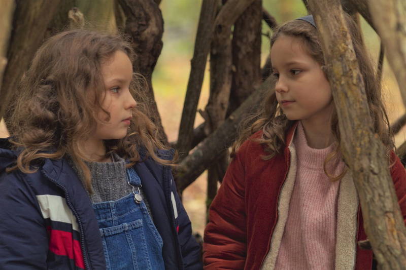 真っ赤に染まった秋の森　一緒に作った小屋を眺める2人の少女　「秘密の森の、その向こう」場面写真