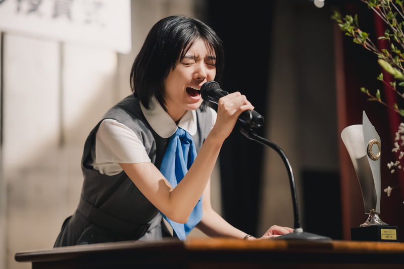 藤吉夏鈴が熱いスピーチ　ドアから何かをのぞく姿も　多彩な表情を見せる　「新米記者トロッ子」場面写真
