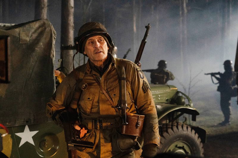 不気味な笑みを見せるミッキー・ローク　白骨死体を見つける兵士　「ウォーハント 魔界戦線」場面写真