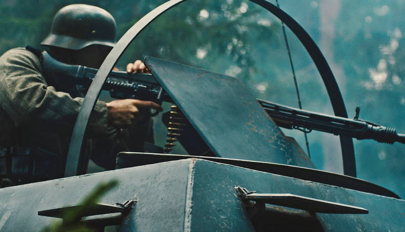 不気味な笑みを見せるミッキー・ローク　白骨死体を見つける兵士　「ウォーハント 魔界戦線」場面写真