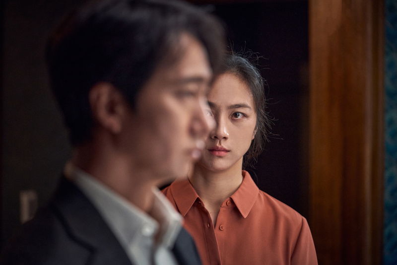 涙をたたえて見つめ合う、崖から転落死した男の妻と取り調べる刑事　「別れる決心」場面写真